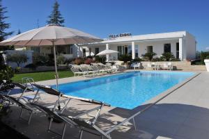 a pool with chairs and an umbrella in front of a building at Villa Emma in Montegranaro