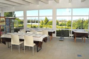 comedor con mesas y sillas y ventanas grandes en Villa Emma, en Montegranaro