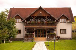 Una casa grande con un balcón con flores. en Pensiunea Sachsenhof, en BÄƒgaciu