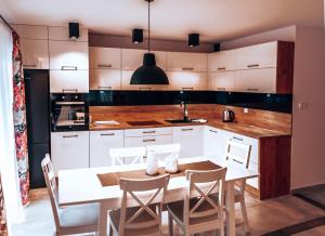 uma cozinha com armários brancos e uma mesa e cadeiras em LB Domek w centrum Willowa 3 em Szczyrk
