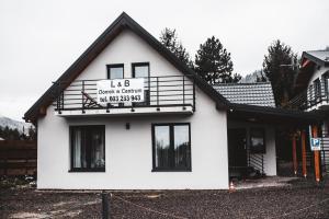 a white house with a sign on the side of it at LB Domek w centrum Willowa 3 in Szczyrk