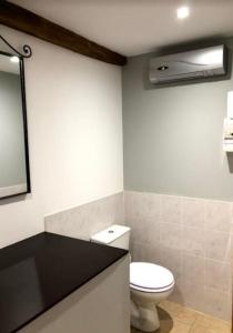 La salle de bains est pourvue de toilettes blanches et d'un miroir. dans l'établissement Gîte du four à pain, à Couzon