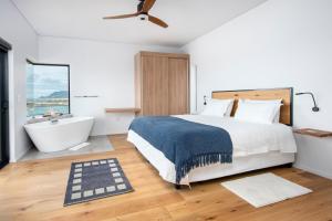 a bedroom with a large bed and a bath tub and a sink at OnTheRocksBB Solar Powered Guesthouse and Ocean Lodge in Bettyʼs Bay