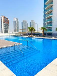 a large swimming pool in a city with tall buildings at Gorgeous Apt In DAMAC HILLS - Golf View in Dubai