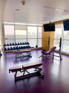 a gym with benches and a flat screen tv at Gorgeous Apt In DAMAC HILLS - Golf View in Dubai