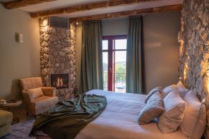 a bedroom with a bed and a chair and a fireplace at Rouista Tzoumerka Resort in Vourgareli
