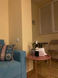 un soggiorno con divano blu e tavolo con una bottiglia di vino di LT-Home a Tbilisi City