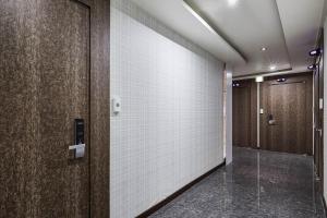 un corridoio con pareti in piastrelle bianche e porte marroni di Galleria Hotel a Suwon