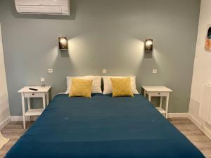 een groot blauw bed in een kamer met 2 tafels bij Le Moulin 3 - Appartement Tout Confort Centre Ville - Beziers - Wifi - Tv connecté in Béziers