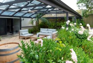 eine Terrasse mit zwei Sofas und ein paar Blumen in der Unterkunft Furche Barossa Vineyard Family Stay 