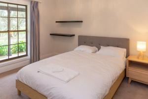Schlafzimmer mit einem großen weißen Bett und einem Fenster in der Unterkunft Furche Barossa Vineyard Family Stay 