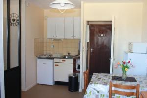 a kitchen with white cabinets and a table and a refrigerator at Studio Barbotan in Barbotan-les-Thermes