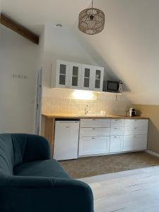 a kitchen with white cabinets and a blue couch at Studio Saint Ayoul in Provins