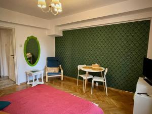 Zimmer mit einem Tisch, Stühlen und einer grünen Wand in der Unterkunft MAYAHouse in Bukarest