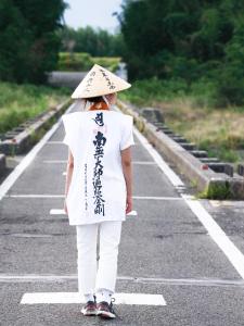 a woman wearing a hat walking down a road at HOSTEL OE in Yoshinogawa