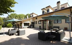 patio con sedie e ombrellone di fronte a un edificio di GREEN GARDEN Resort - Smart Hotel a Mestre