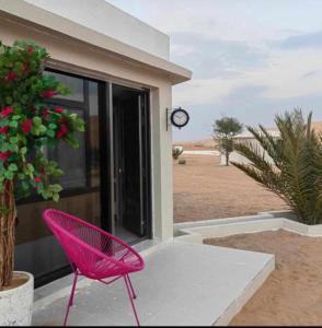 einem rosa Stuhl vor einem Haus mit einer Uhr in der Unterkunft Safari Desert Camp in Shāhiq