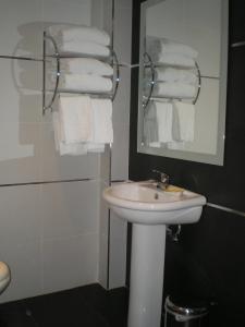 a bathroom with a sink and a mirror and towels at Apartamentos Plaza España Deluxe in Zaragoza