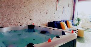 a jacuzzi tub in a room with a couch at Les bulles d'Evanez Mont-saint-Michel jacuzzi intérieur privatif illimité in Pontorson +44 photos