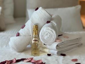 una habitación con una toalla y una botella de perfume en Cocon Blanc câlin - Jacuzzi privatif - Love Room à Saint Etienne en Saint-Étienne