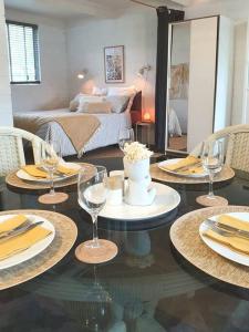 a dining room table with wine glasses and a bedroom at Cute and Quirky Doves Nest Studio Walk to Werri Beach in Gerringong