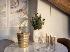 a table with a bottle of champagne and two wine glasses at Cocon Blanc câlin - Jacuzzi privatif - Love Room à Saint Etienne in Saint-Étienne