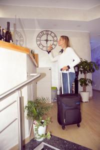 una donna in piedi con una valigia e un orologio di Hotel Fioralba a Milano