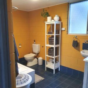 a yellow bathroom with a toilet and a sink at Cute and Quirky Doves Nest Studio Walk to Werri Beach in Gerringong