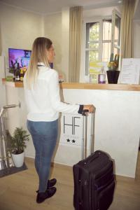 a woman standing with a suitcase at a counter at Hotel Fioralba in Milan