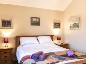 - une chambre avec un lit et des chaussons violets dans l'établissement Newlands Farm Cottage Halifax, à Luddenden Foot