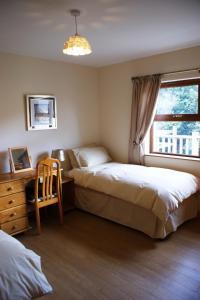 1 dormitorio con 2 camas, escritorio y ventana en Glendun Self Catering, en Cushendall