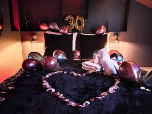 a bed with balloons and a heart on it at Suite Rouge baiser avec Jacuzzi privatif - LoveRoom Insolite in Saint-Étienne
