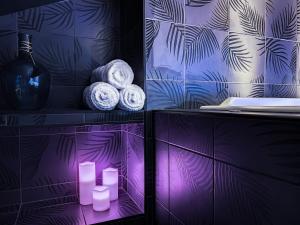 Baño púrpura con toallas y velas en un estante en Suite Privative Rouge baiser - Spa & Jacuzzi - Love Room à Saint Etienne en Saint-Étienne