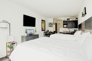 a white bedroom with a large white bed and a kitchen at Landmark Resort 1208 in Myrtle Beach
