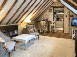 sala de estar con techos de madera, mesa y sillas en Old Rectory Loft, en Fernhurst