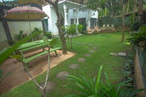 a garden with a green bench and an umbrella at Percy Residence in Unawatuna