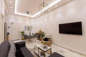 a living room with a couch and a tv on a wall at Airport Apartment Suite Casablanca FREE WIFI Modern Confort Calme in Derroua