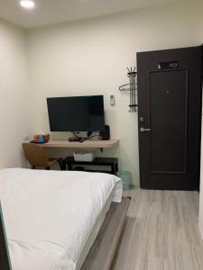 a bedroom with a bed and a desk with a television at 晶晶輕旅民宿 in Ruifang