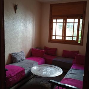 ein Wohnzimmer mit lila Sofas und einem Tisch in der Unterkunft Raha in Fès