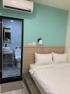 晶晶輕旅民宿 في Ruifang: غرفة نوم بسرير وحمام مع مرحاض