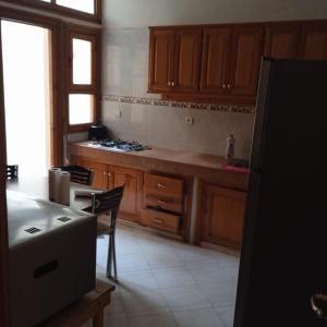 eine Küche mit Holzschränken, einem Tisch und einem Kühlschrank in der Unterkunft Raha in Fès