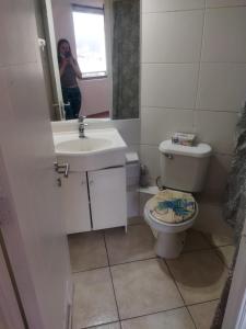 una mujer tomando una foto de un baño con aseo y lavabo en Coraceros Apartment, en Viña del Mar