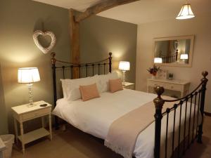 a bedroom with a large bed and a heart mirror at Cowpasture Barn B&B in Eye