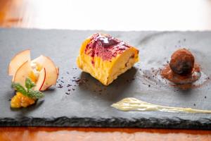 un piatto nero con un pezzo di torta e frutta di Villa Montpetre a Kirishima