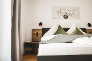 um quarto com uma cama com almofadas brancas e verdes em Imi Appartement em Eben im Pongau