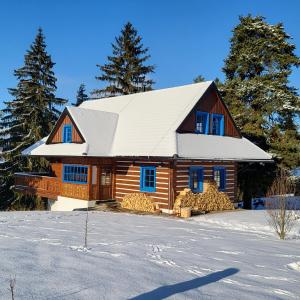 uma cabana de madeira com um telhado branco na neve em Tri borovice em Liptovský Mikuláš