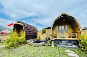 Tegal Bamboo cottages & private hot spring في Baturaja: منزل مع منزل خشبي كبير مع حديقة