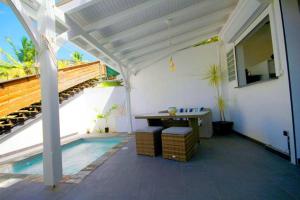 un patio blanc avec une table et une piscine dans l'établissement T2 design pour 2 à Anse à l'Âne aux Trois Ilets, à Les Trois-Îlets