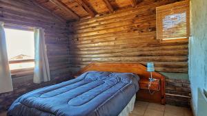 a bedroom with a bed in a wooden cabin at Cabañas Premium Mirador Azul in Potrerillos