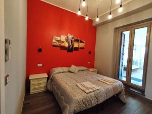 een slaapkamer met een rode muur, een bed en een raam bij The Junior House - Casa Vacanza in Lauria Inferiore